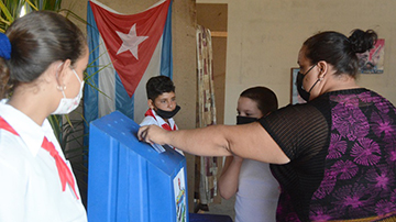 Mujer votando en una urna custodiada por pioneros